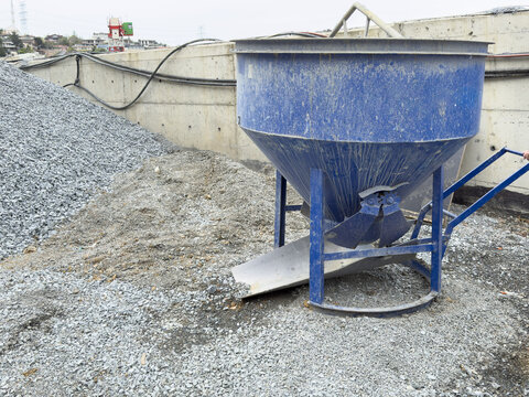 View of a blue concrete bucket hopper standing next to piles of crushed stone and gravel at a construction site in Sariyer, Istanbul, Turkiye.