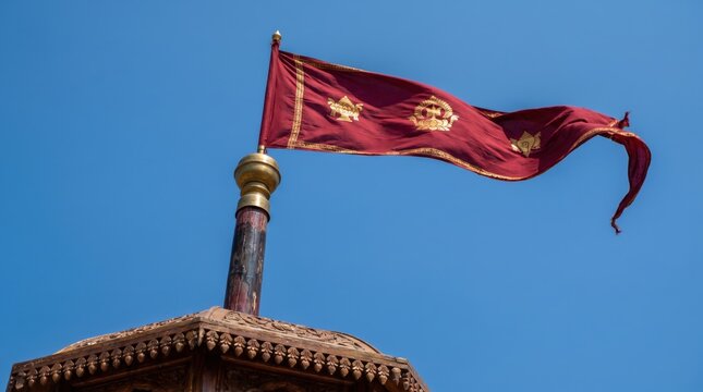 Maroon and Gold Buddhist Flag Flying Against Blue Sky