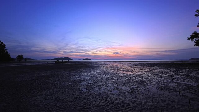 Twilight tidal shoreline with distant islands beneath layered pastel sky
