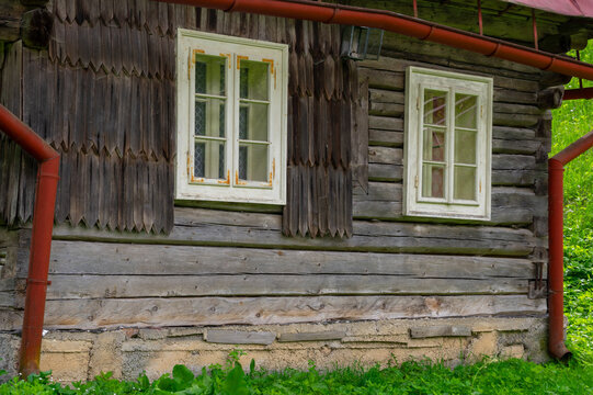 View of the traditional wooden architecture at the Former charcoal workers' settlement Moce with weathered log walls and white windows in Motycky, Banska Bystrica, Slovakia.