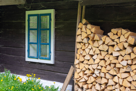 View of the Former charcoal workers' settlement Moce with a traditional wooden log cabin, blue window frame and stacked firewood in Motycky, Banska Bystrica Region, Slovakia.