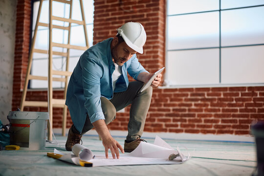 Architect using touchpad while working on blueprints during home remodeling project.