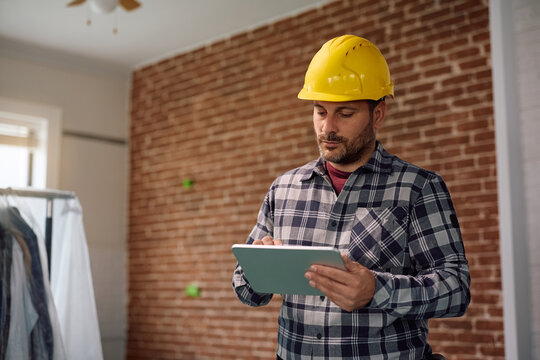 Manual worker working on touchpad during home remodeling project.