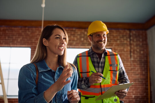 Happy woman communicating with construction worker during home remodeling project.