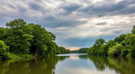 Fototapeta premium Peaceful river landscape with green trees and dramatic cloudy sky