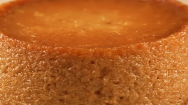 Extreme close-up macro shot of the edge of a sweet caramel custard dessert or flan, highlighting the smooth golden surface and textured baked side.