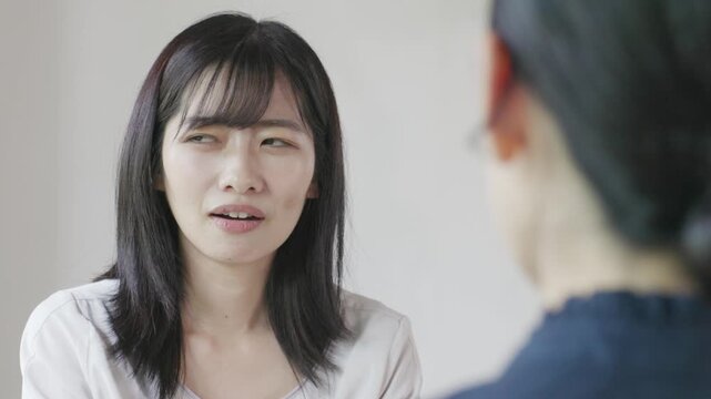 Young Asian woman smiling and talking while using laptop