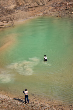 Woman photographs friend wading in green water