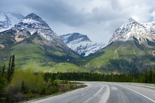 Winding road in Yoho National Park with snow capped mountains