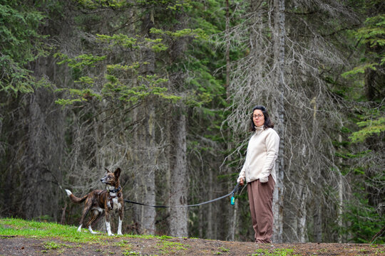Woman and dog enjoying a walk on a trail through a green forest