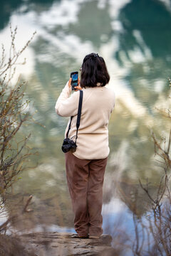Woman taking a photo of a lake with a smartphone
