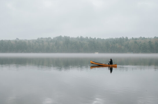 Lone person canoeing on a calm misty lake