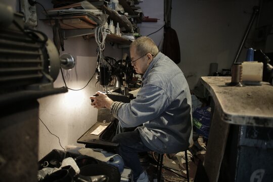 Elderly Asian artisan repairing a shoe in his workshop