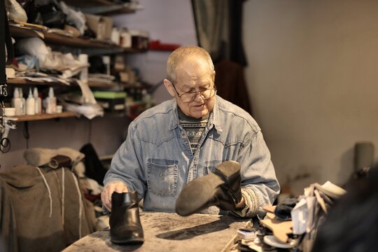 Senior shoemaker repairing a leather boot in his workshop