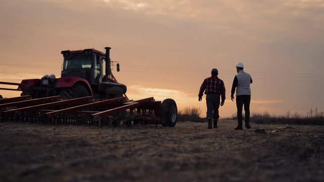 Agronomist and builder walking in fields, back view of people in farmland. Modern agricultural technology and machinery, innovation in agriculture, farmer and bioengineering examining farmland