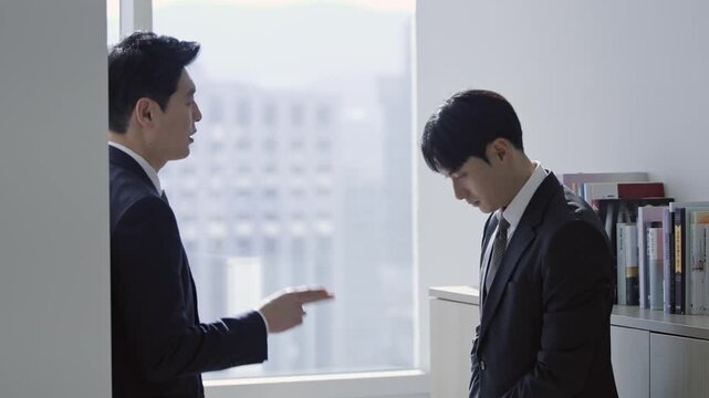 Serious business discussion: Asian boss scolding male employee in modern office, illustrating workplace conflict, performance review, or corporate stress.