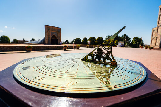 Ancient stone sundial at Ulugh Beg Observatory in Samarkand, Uzbekistan, with the historical building remains visible in the background under a clear blue sky.