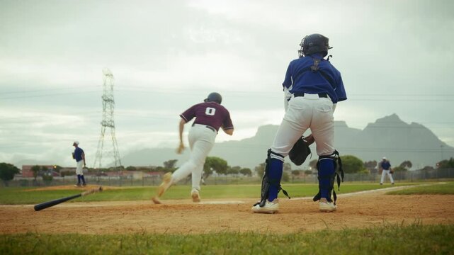 Focused baseball batter connects with the pitch, sending the ball into play. The catcher follows the action on the field as the runner heads to first base.