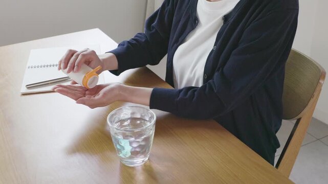 Close-up of woman's hands taking pills out of bottle