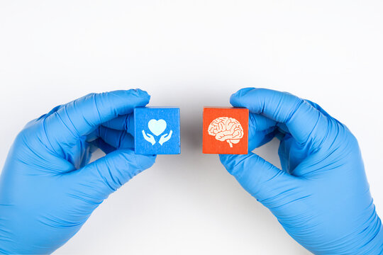 Concept of brain function, clinical evaluation, and prevention of neurological diseases. A doctor's hand wearing light blue gloves arranges wooden cubes with brain icons.
