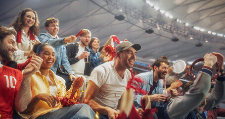 Naklejka premium Diverse Fans at a Soccer Football Championship Laugh, Shout and Clap in Stadium Seating After a Crucial Moment, Waving Red Scarves and a Tambourine as Relief and Joy Spread Across Their Faces.