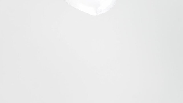 Transparent liquid serum, peptide dripping from a plastic cosmetic spatula, close-up.