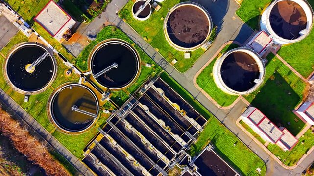 Straight down bird's eye view of round clarifiers and rectangular aeration pools at a purification site. Overhead view of sewage treatment facility tanks.