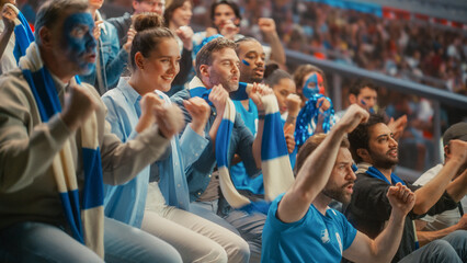 Naklejka premium Diverse Crowd of Excited Male and Female Fans With Painted Faces and Blue Scarves Watching a Tense Soccer Football Championship Match in Stadium Stands, Happy Smiling Supporters Cheer for Their Team.