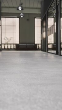 A hallway is shown with smooth flooring and windows allowing light to enter. Chairs are placed in the background. The scene depicts a simple indoor space during the day.