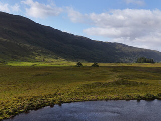 Naklejka premium Aerial View of Lush Scottish Highland Valley with River and Mountains