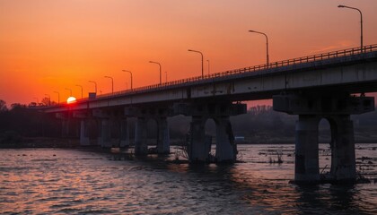 Fototapeta premium The sun is setting over a bridge over a large body of water