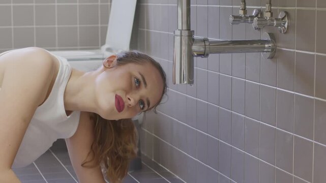 Worried young woman looking at leaking pipe under bathroom sink home emergency