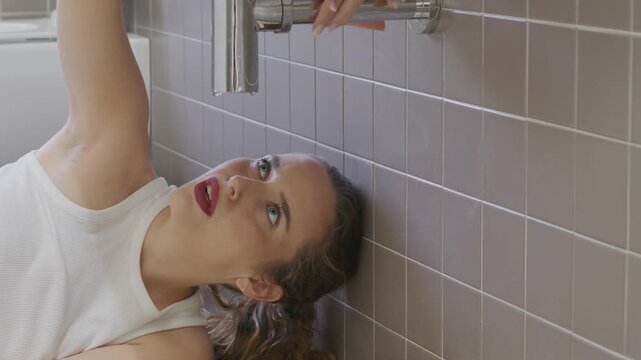Worried young woman looking at leaking pipe under bathroom sink home emergency