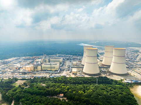 Aerial view of Rooppur Nuclear Power Plant with its four cooling towers and reactor buildings surrounded by forests near a river in Pakuria, Rajshahi Division, Bangladesh.