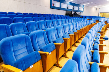 Naklejka premium Rows of empty blue velvet seats in a modern conference theater or cinema hall. Interior of an auditorium for public speech