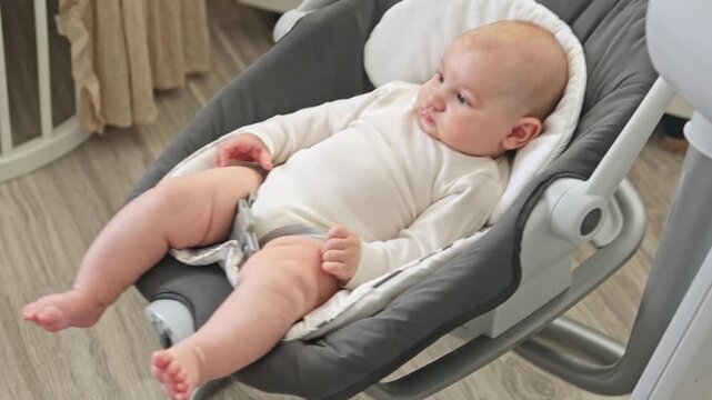 Cute baby boy learning to roll over from back to tummy on a soft bed. Sweet infant development milestone, active moving in nursery room. Early childhood, growth and parenting concept.