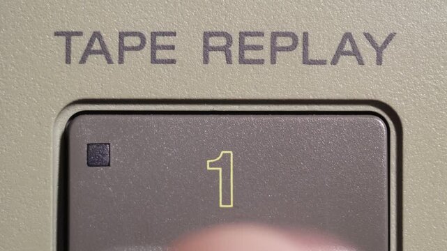 Finger presses tape replay button marked 1 on vintage editing remote controller