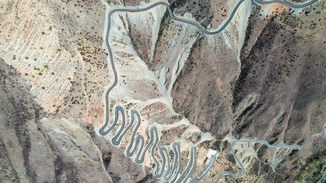 Drone view of winding road on Muma mountains in Jinchuan country, Aba Tibetan and Qiang Autonomous Prefecture, Sichuan, China. 4k real time top down footage, travel concept.