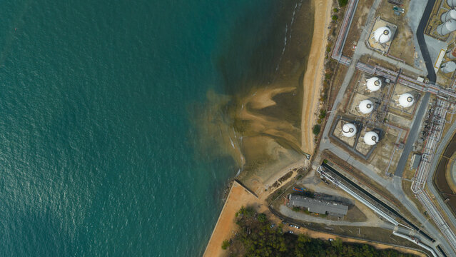 Aerial view of the Bangchak Sriracha Refinery featuring spherical storage tanks and industrial infrastructure along the coast in Si Racha District, Chon Buri, Thailand.