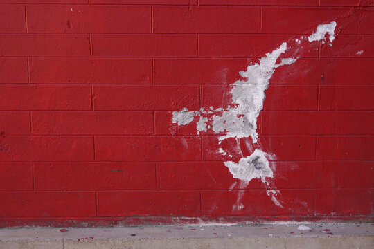Red brick wall with peeling paint showing white surface