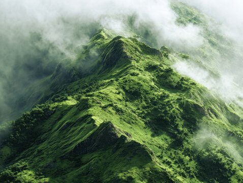 Aerial view of lush green mountain ridge enveloped in mist and clouds showcasing vibrant nature and serene landscape scenery