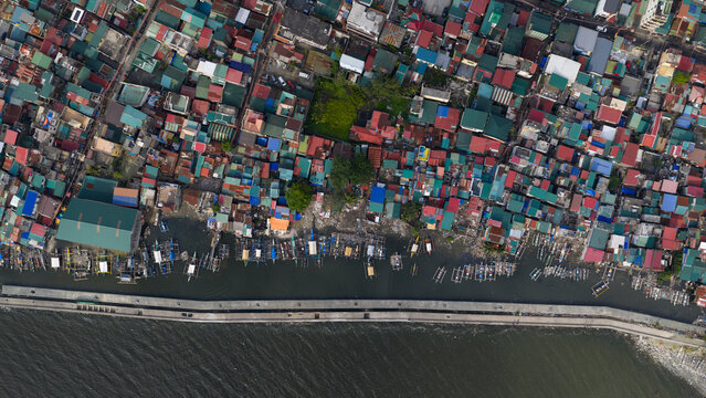 Aerial view of densely packed colorful rooftops and outrigger boats along the concrete seawall in Manila, Metro Manila, Philippines.