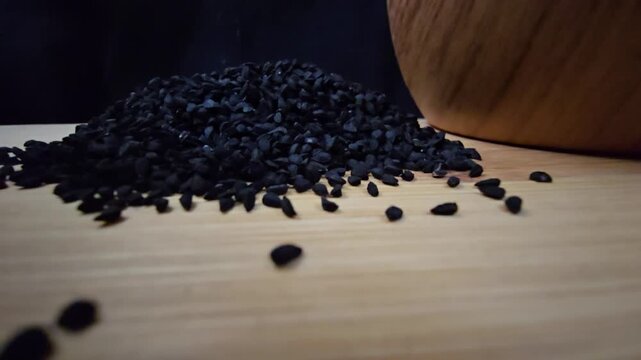 Macro shot of black seed, also known as nigella sativa or kalonji, spilling from a wooden bowl, perfect for herbal medicine and healthy food concepts.