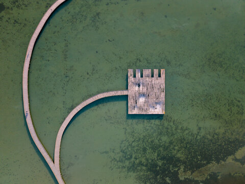 Aerial view of the wooden bridge and platform over the turquoise waters of Narta Lagoon near St. Mary's Monastery in Zvernec, Vlore County, Albania.
