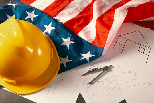 Helmet and blueprints with American flag on table close-up
