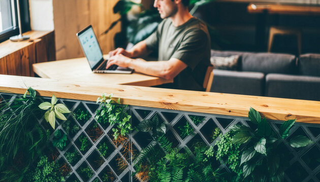 Modern interior partition with vibrant green plants and person working on laptop