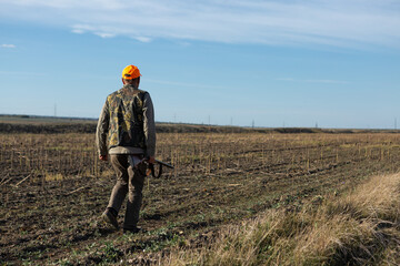 Fototapeta premium Mature man hunter with gun while walking on field.
