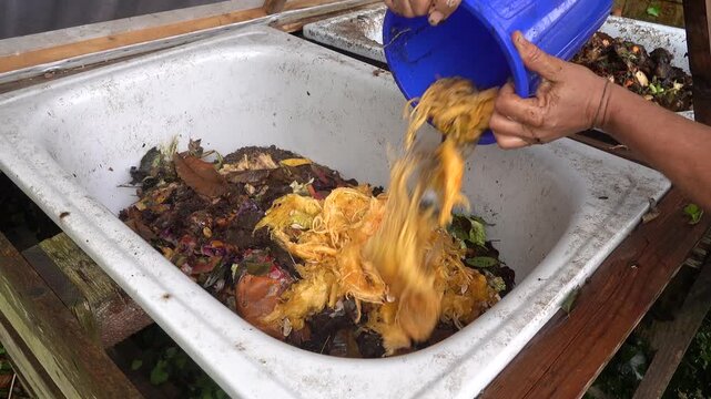 Man emptying kitchen organic waste into a backyard compost bin for recycling