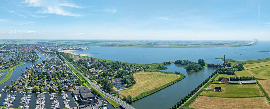 Aerial view of Lemmer featuring a marina, residential houses, green fields, and the historic Woudagemaal steam pumping station by the water Lemmer, Friesland, Netherlands.