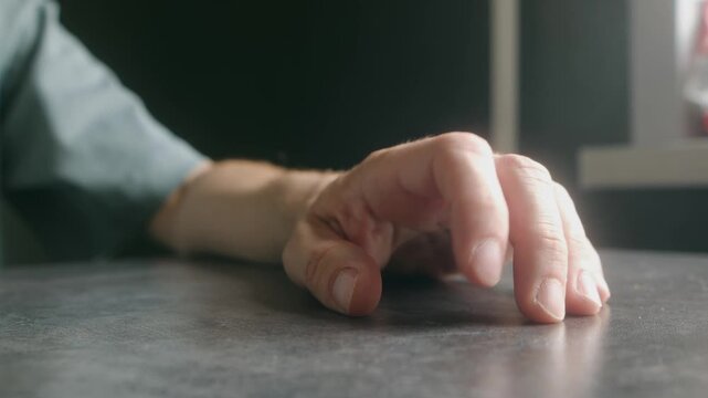 Close up man hand with fingers drumming nervously on dark table, expressing impatience, boredom, or anxiety while waiting for something or someone in room. Man tapping fingers showing impatience